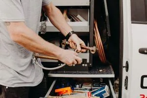 Plumber preparing tools and fittings beside a Jetty Plumbing work vehicle