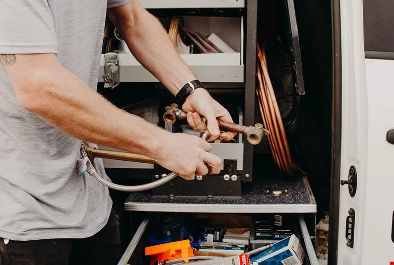 Gas fitter preparing copper pipework and fittings beside a service van