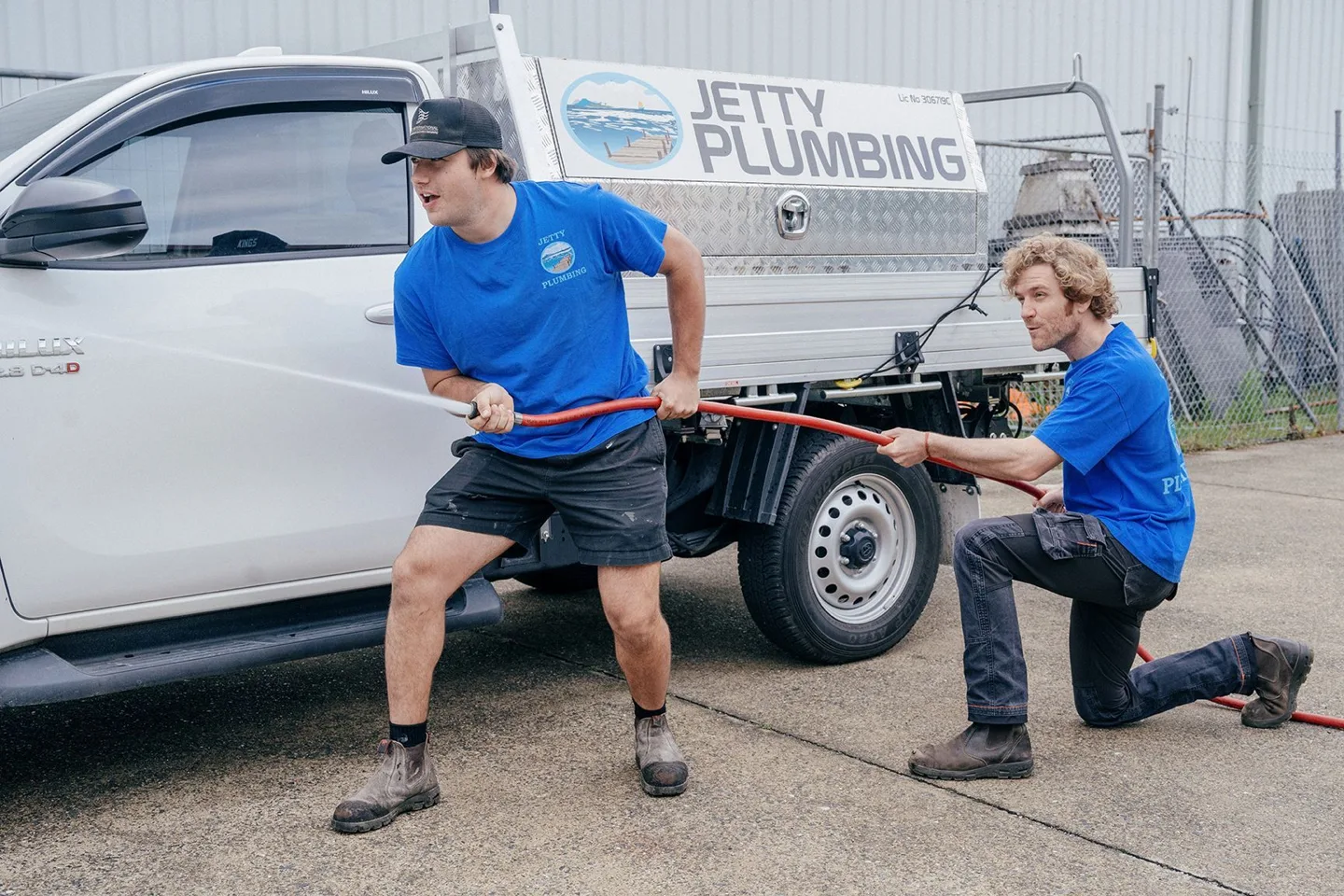 Jetty Plumbing team members with a hose at a plumbing job
