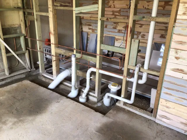 Exposed waste and water pipes within wall framing during a renovation