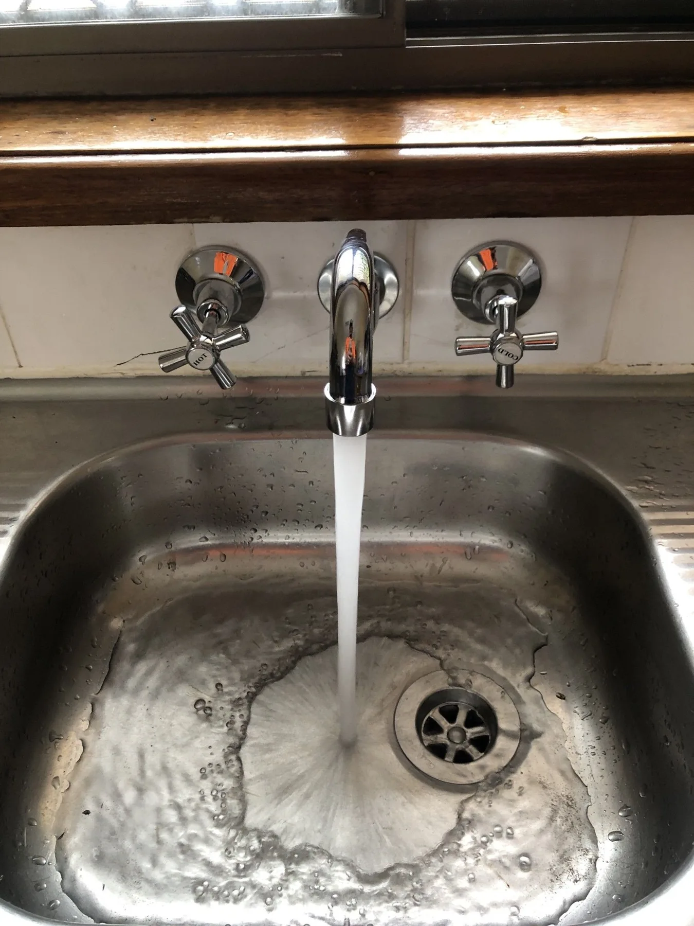 Water flowing from a kitchen tap over a sink
